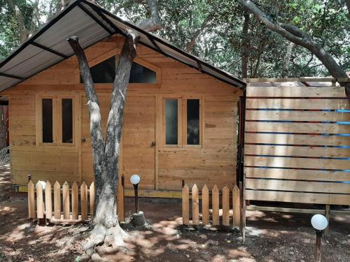 a wooden cabin with a fence and a tree at Nature Glamping in Matheran