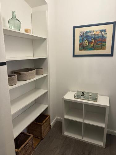 ein weißes Bücherregal mit einem Tisch in einem Zimmer in der Unterkunft Gemütliches Appartement "Emma" in Halle in Rusches Hof