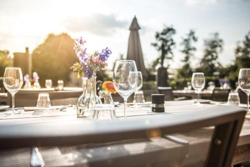 uma mesa com copos de vinho e flores em Erfgoed Bossem em Lattrop