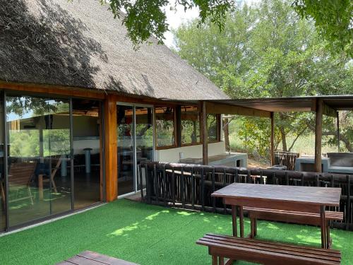 una casa con tetto di paglia, tavolo e panche di Letaba Waterfront Lodge a Letaba Wildlife Reserve