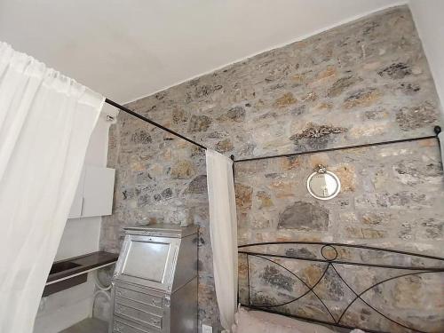 Habitación con pared de piedra, ventana y cortina. en Monolocale con bagno e angolo cottura Nido in Toscana, en Monterotondo