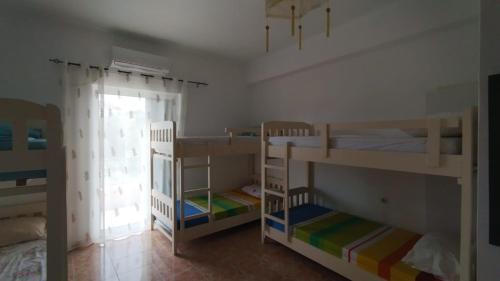 a room with three bunk beds and a window at Oasis Hostel in Himare