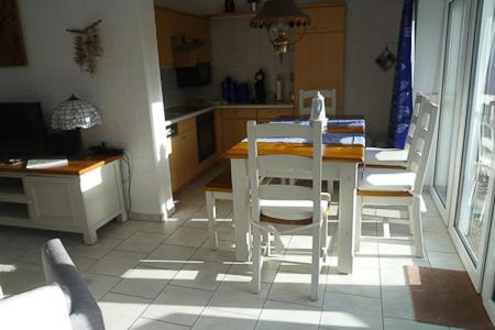a kitchen with a table and white chairs in a room at Ferienhaus Treibholz in Neuharlingersiel