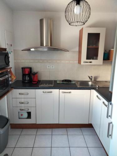 une petite cuisine avec des armoires blanches et un évier dans l'établissement IRIS, à Aigues-Mortes