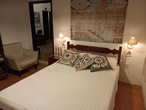 um quarto com uma cama com almofadas e uma cadeira em Sítio das Pedras em Matias Barbosa