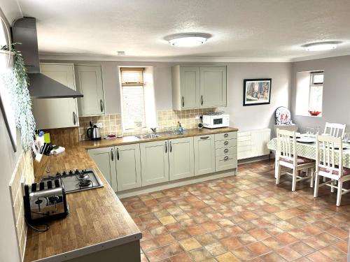 a kitchen with white cabinets and a table in it at The Old Barn - Bramble Farm Cottages in Ferndown