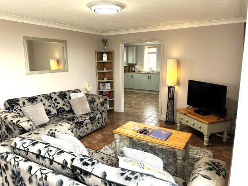 Sala de estar con sofás, mesa y TV en The Old Barn - Bramble Farm Cottages en Ferndown
