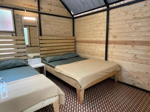 two beds in a room with wooden walls at Nature Glamping in Matheran