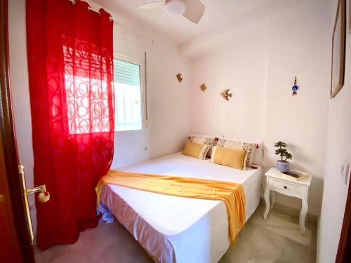 1 dormitorio pequeño con 1 cama con cortina roja en MyChoice Pitiusa by Bossh! Apartments, en Rota
