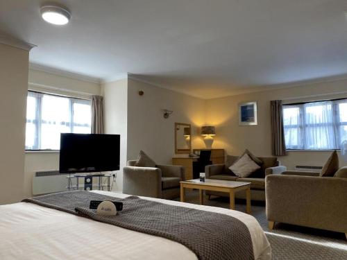 Habitación de hotel con cama y sala de estar. en The Wiltshire Hotel, Golf and Leisure Resort, en Swindon