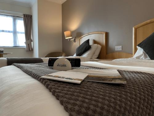 um quarto de hotel com uma cama com um livro em The Wiltshire Hotel, Golf and Leisure Resort em Swindon