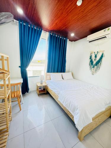 a bedroom with a large bed with blue curtains at Vile Villa Homestay View Biển 01 Đảo Phú Quý in Cu Lao Thu