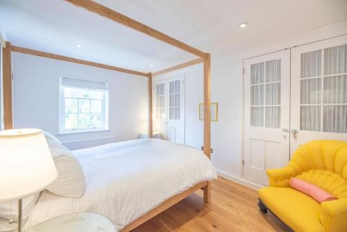 a bedroom with a bed and a yellow chair at 8 Bredfield Street in Woodbridge