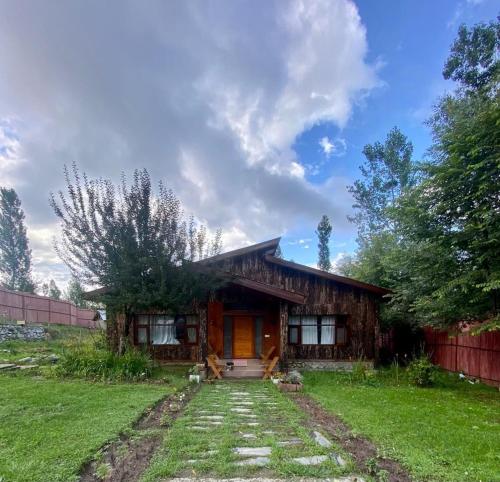 a small wooden house with a grassy yard at JK's The Trout Stream in Gulmarg