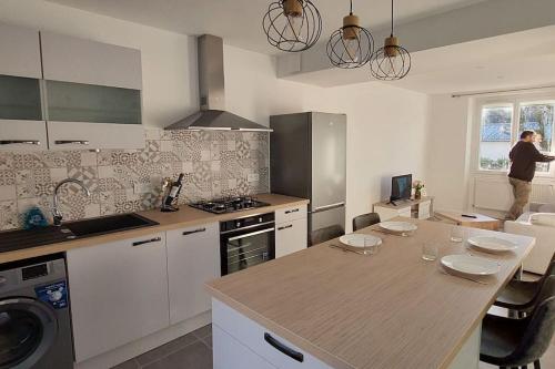 une cuisine avec un comptoir et une personne debout à la fenêtre dans l'établissement Appartement proche du Château., à Arnac-Pompadour