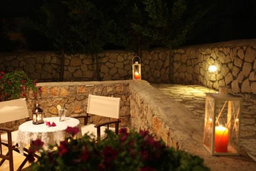 un tavolo, due sedie e un muro di pietra di Porto Nirikos a Città di Lefkada