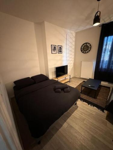 - une chambre avec un lit, une table et une horloge dans l'établissement Black Studio, au Havre