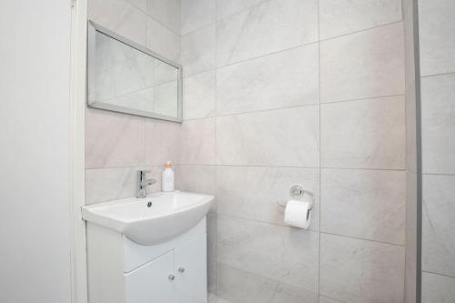 a white bathroom with a sink and a mirror at The Races, Portland Place. in Cheltenham