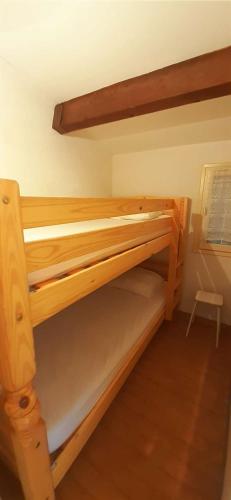 Ce lit superposé en bois se trouve dans un dortoir. dans l'établissement TERRASSES DE LA PLAGE Joli T2 cabine proche plage Richelieu Cap d'Agde TERRASSES DE LA PLAGE, au Cap d'Agde