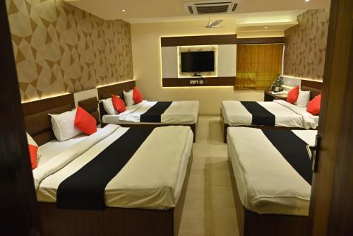 Habitación de hotel con 4 camas con almohadas rojas en Hotel Royal Cottage en Kānpur