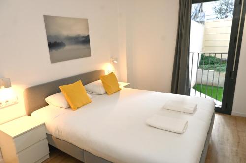 a bedroom with a white bed with two yellow pillows at Homenfun Barcelona Can Serra in Hospitalet de Llobregat