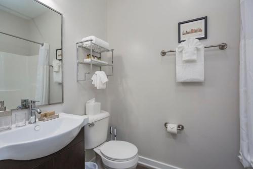La salle de bains blanche est pourvue d'un lavabo et de toilettes. dans l'établissement Cozysuites Music Row Stylish 2BR-free parking 59, à Nashville