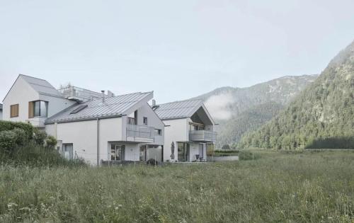 a house in a field with mountains in the background at TIROLER TRIS modern villa 10 beds in Maurach
