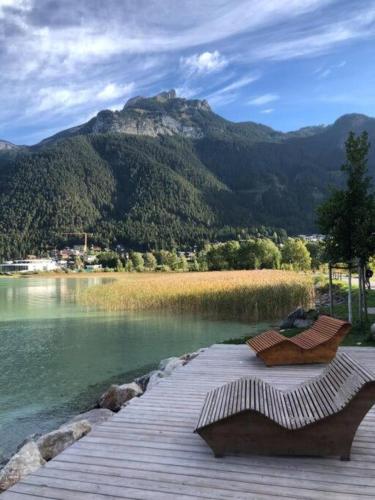 a couple of benches sitting on a boardwalk next to a lake at TIROLER TRIS modern villa 10 beds in Maurach