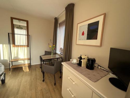 Cette chambre d'hôtel dispose d'un bureau et d'une table avec une télévision. dans l'établissement Casa Hermosa, à Sassenheim