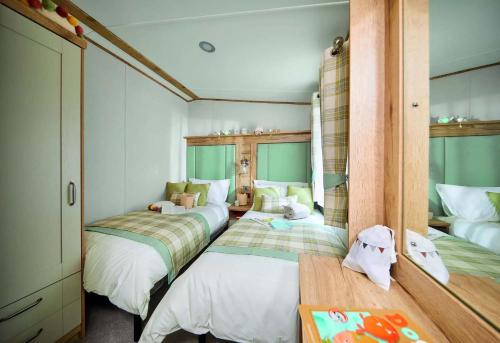 a bedroom with three beds and a table in it at Springwood Holiday Park in Kelso