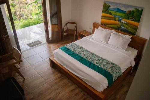 Un dormitorio con una cama con un cuadro en la pared. en Sastra Ubud House, en Ubud