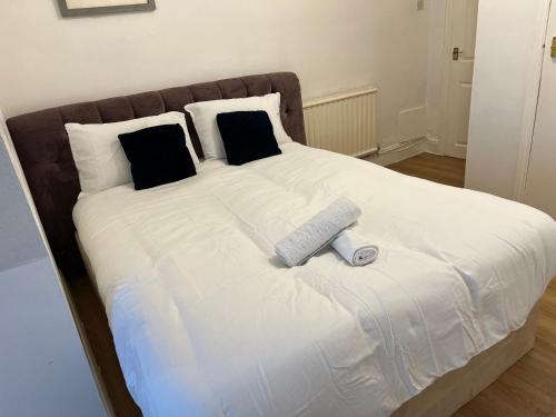 a large bed with white sheets and black pillows at De Luxe apartment 1 in Leicester