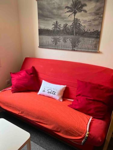 - un canapé rouge avec un oreiller dans l'établissement Hyper Centre Ville, le Brion, à Sète