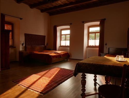 a bedroom with two beds and a table and two windows at Úrágya Vendégház in Mád