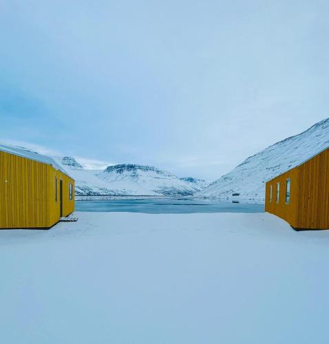 einen Blick auf zwei Gebäude auf einem schneebedeckten Hang in der Unterkunft Fisk Club Cottages in Suðureyri