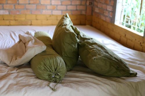 two green pillows sitting on top of a bed at hugs stay nam ban in Hoat