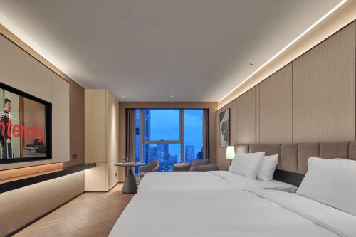 una camera d'albergo con un letto grande e una grande finestra di Hefei Huiyan Anhui Center Intercity Hotel a Hefei