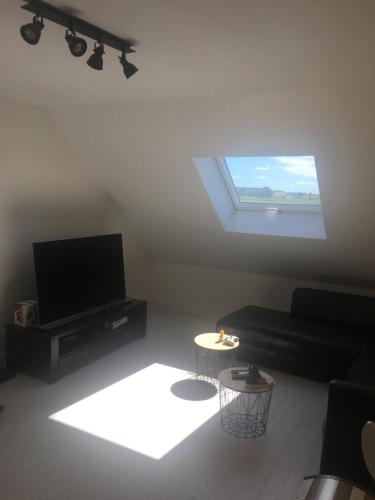 ein Wohnzimmer mit einem Flachbild-TV und einem Fenster in der Unterkunft Maison 24H du Mans in Teloché