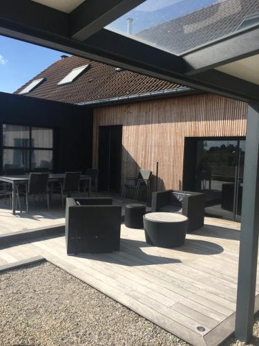 eine Terrasse mit Tischen und Stühlen auf einem Gebäude in der Unterkunft Maison 24H du Mans in Teloché