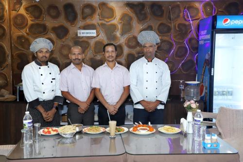 a group of chefs standing next to a table with food at De Falcon Goa Beach Resort in Candolim