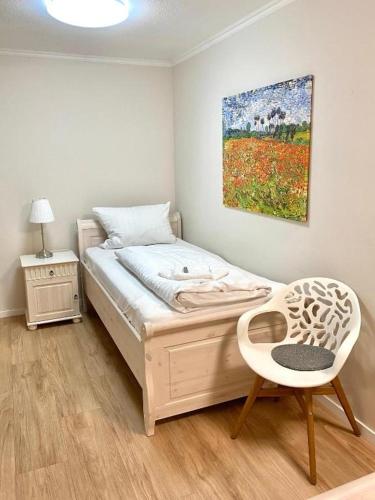 a bedroom with a bed with a chair and a painting at Landhaus Fillerberg in Wildeshausen