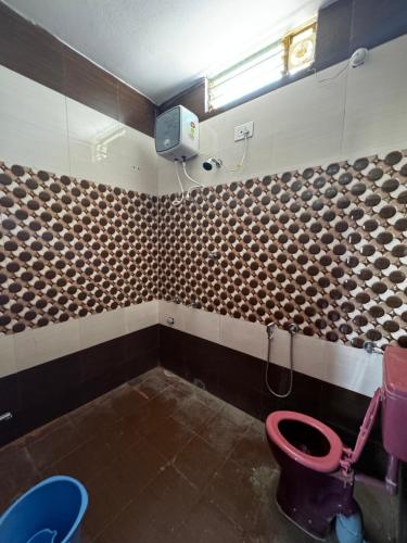 a bathroom with a toilet and a tv on the wall at JP HOME STAY in Tiruvannāmalai
