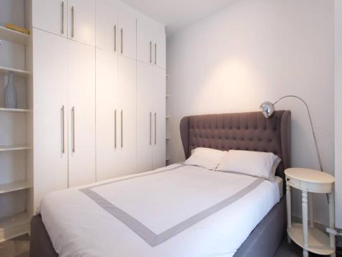 Schlafzimmer mit einem Bett mit weißen Schränken und einer Lampe in der Unterkunft Paddington Apartment 5mins from St Mary Hospital Pass the Keys in London