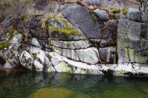 a rock wall next to a body of water at Casa dos Toros in Cortes do Meio