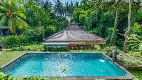 a swimming pool in front of a house with a gazebo at As I Am Ubud Retreat in Ubud