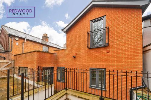 an orange brick building with a black fence at Festival Serviced Apartment, Perfect of Contractors & Families FREE Wifi & Netflix By REDWOOD STAYS in Basingstoke