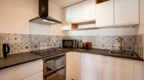 une cuisine avec des armoires blanches et un évier dans l'établissement Home Chic Home - Les Toits de Sainte-Ursule, à Montpellier