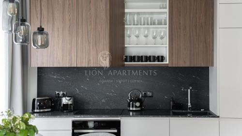 a kitchen with wooden cabinets and a black counter top at Lion Apartments - SCALA City Center Apartments&Studio IIA in Gdańsk