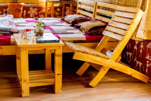 una sedia in legno e un tavolo con un letto di VedKasturi Farmstay - Agrotourism a Giravali