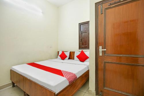 ein Schlafzimmer mit einem Bett mit roten Kissen und einer Tür in der Unterkunft Wave Inn Guest House in Ludhiana